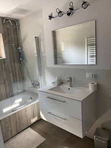 ein Badezimmer mit einem Waschbecken, einer Badewanne und einem Spiegel in der Unterkunft Domek „Na Górkach” in Grybów
