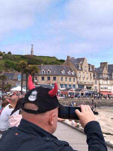 un homme prenant une photo de la plage avec une personne portant un chapeau de diable dans l'établissement LA PORTE BLEUE, à Cancale