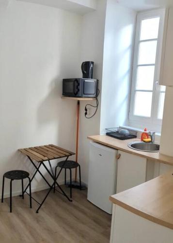 La cuisine est équipée d'un évier, d'une table et d'un four micro-ondes. dans l'établissement Studio mezzanine, à Foix