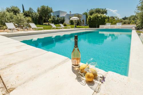 a bottle of wine sitting next to a swimming pool at New Villa Filara with Sea view Pool in Specchiolla 