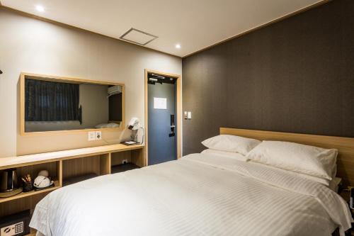 a bedroom with a large white bed and a television at About Stay Seoul in Seoul