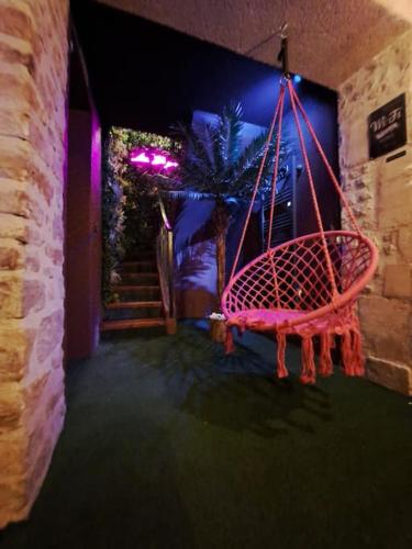 a swing hanging from a wall in a room at La Bayeuzen - La Tropicale - Love Room in Bayeux