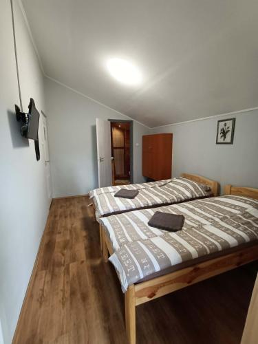 two beds in a small room with wooden floors at Tölgyfa Vendégház in Balatonszepezd