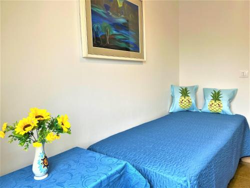 Un dormitorio con una cama azul y un jarrón con flores en Casa MARINA en Scalea