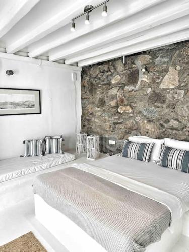 a bedroom with two beds and a stone wall at Mykonos lovely apartment in Mikonos