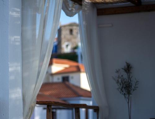 a window with white curtains with a view of a building at Chora Suite in Alonnisos Old Town