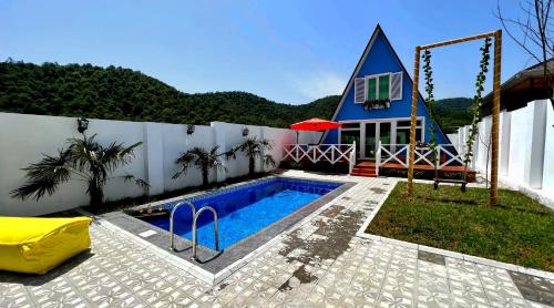 a swimming pool in front of a house with a church at Qafqaz Resort Melisa in Gabala