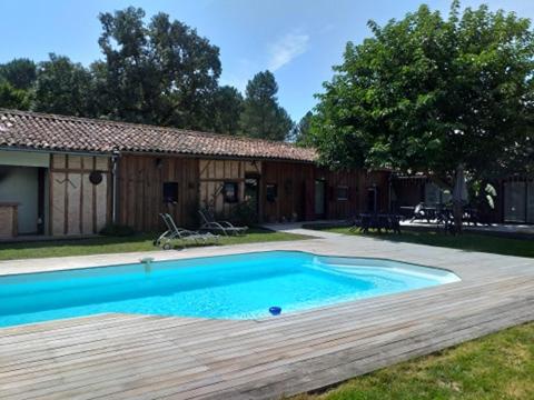 - une piscine avec une terrasse en bois à côté d'une maison dans l'établissement LE PETIT CELTIS, 
