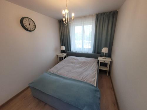 - une chambre avec un lit et une horloge murale dans l'établissement Golden Apartament, à Szczecin