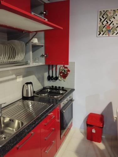 a kitchen with red cabinets and a stove at ARIA Apartament in Durrës