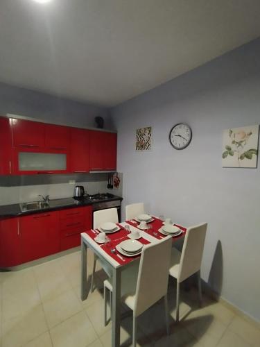 a kitchen with a table with chairs and a clock on the wall at ARIA Apartament in Durrës