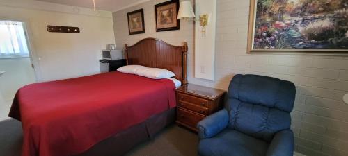 a bedroom with a bed and a chair in it at Husker Inn in North Platte