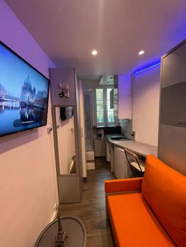 un salon avec un canapé orange et une cuisine dans l'établissement Chambre proche arc de triomphe, à Paris