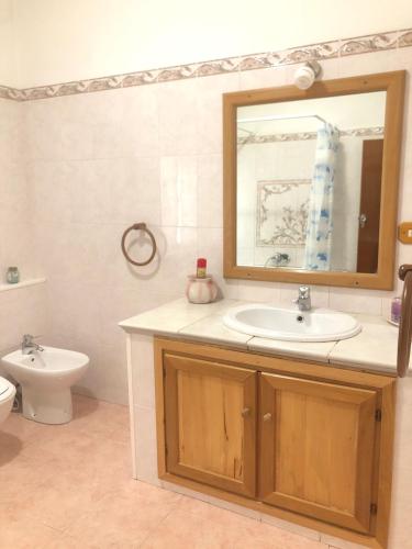 a bathroom with a sink and a toilet and a mirror at A casa di Maria in Ozieri