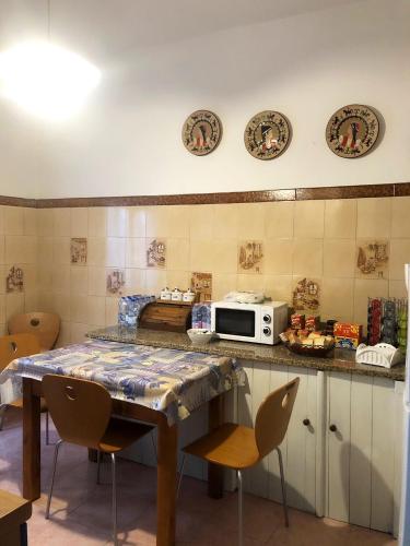 a kitchen with a table with chairs and a microwave at A casa di Maria in Ozieri