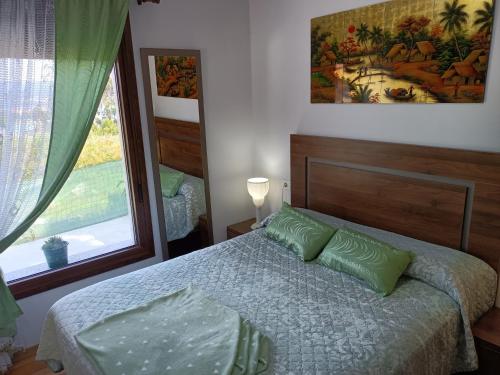 Un dormitorio con una cama con almohadas verdes y una ventana en Preciosa casa con aparcamiento a 1km de la Toja, en O Grove