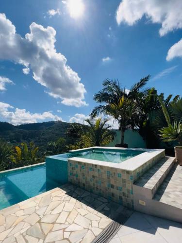 a swimming pool with a blue sky and palm trees at SÍTIO MARAVILHOSO EM MAIRIPORÃ opção de 1 quarto para 8 pessoas ou 4 quartos acima de 9 pessoas in Mairiporã