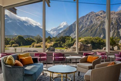 a lobby with a large window with mountains in the background at The Hermitage Hotel Mt Cook in Mount Cook Village