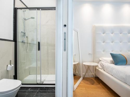 a bathroom with a shower and a toilet and a bed at PLEY Boutique Del Centro in Cagliari
