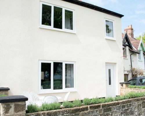 a white house with two white chairs in front of it at Relaxing Cottage Escape - Pub - Fire - King Size Bed in Newton Aycliffe
