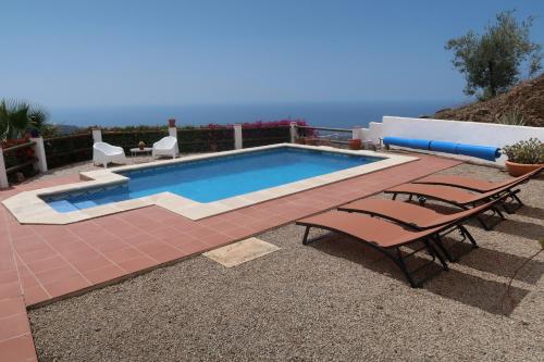 una piscina con 2 sillas y una mesa en Villa Los Naranjos, en Sayalonga
