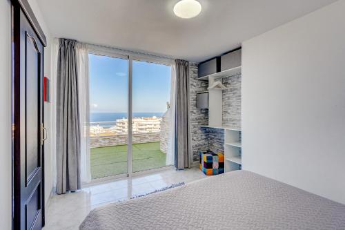 Un dormitorio con una cama y una ventana grande. en Luxury apartment with stunning ocean view, en Puerto de Santiago