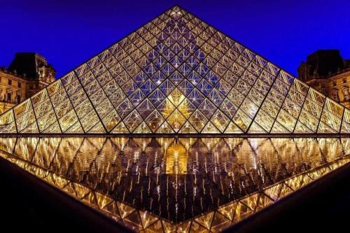 uma vista para um edifício em forma de pirâmide à noite em Bel appartement /30 min de Paris em Louveciennes