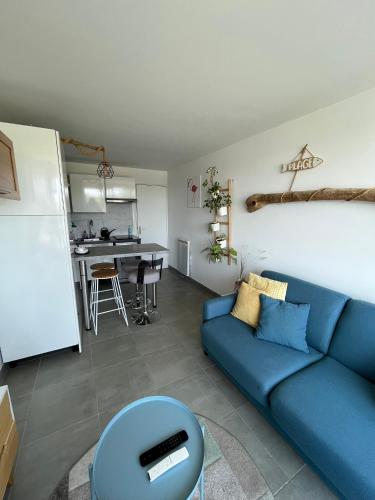 un salon avec un canapé bleu et une cuisine dans l'établissement Studio port camargues, au Grau-du-Roi