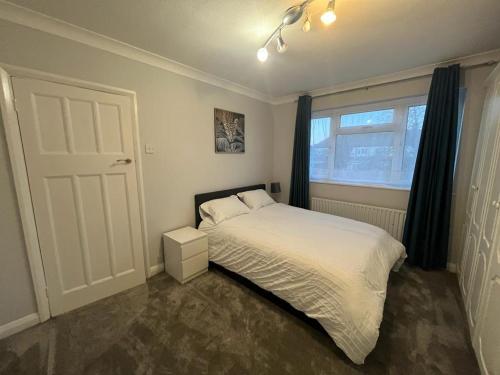 1 dormitorio con cama blanca y ventana en Gants hill, en Barkingside
