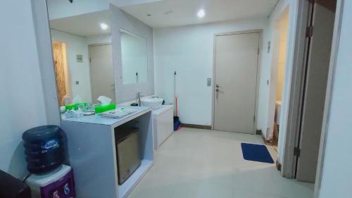 uma cozinha branca com um lavatório e uma televisão em Apartment Centerpoint by RR Property em Kayuringin