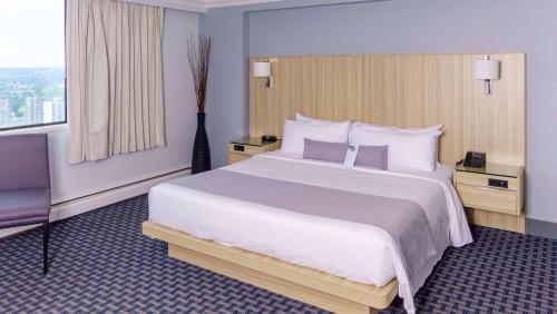 a hotel room with a large bed and a window at Century Plaza Hotel in Vancouver