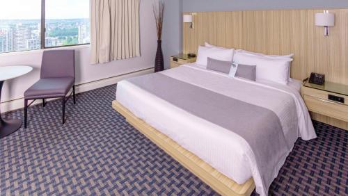a hotel room with a large bed and a table at Century Plaza Hotel in Vancouver