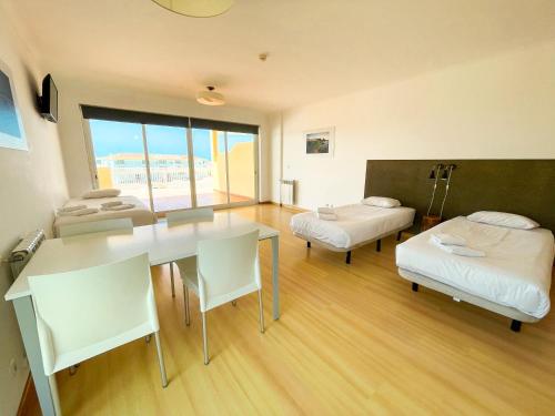 a room with two beds and a desk and a table at HI Santa Cruz - Pousada de Juventude in Santa Cruz