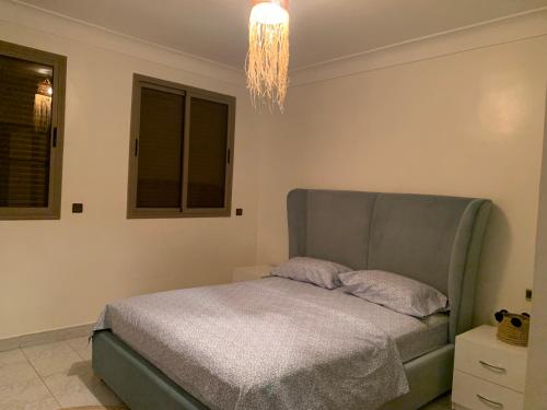 Schlafzimmer mit einem Bett und einem Kronleuchter in der Unterkunft APPARTEMENT PERLE RARE AU CENTRE DE MARRAKECH in Marrakesch