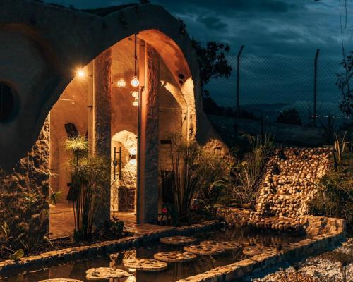 un edificio de piedra con un jardín acuático por la noche en Pachamama finca hotel - spa en Dosquebradas
