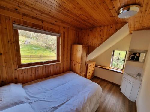 a bedroom with a bed and a window in a cabin at Altdarroch Farm House in Kinlocheil