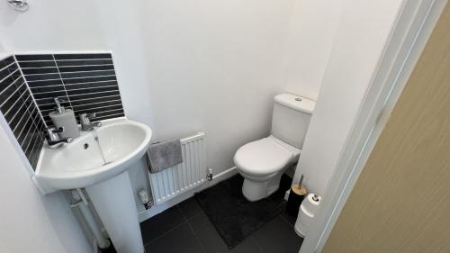 a bathroom with a white sink and a toilet at Large, spacious and cosy 5 bedroom house at Broughton, Sleeps up to 9 guests. Located just off junction 14 of the M1, it is perfectly located and a short drive to Milton Keynes City Centre, Train Station, Gulliver's Theme Park, Intu Shopping Centre. in Broughton