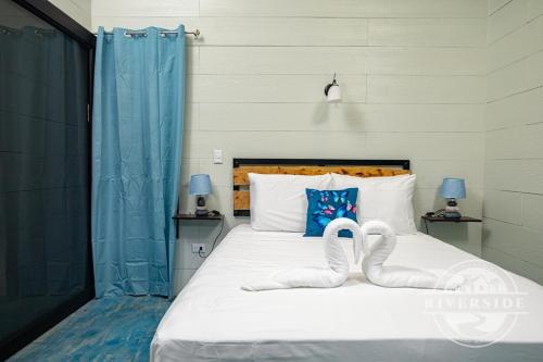 a bed with two swans shaped towels on it at Riverside Villas in Manuel Antonio