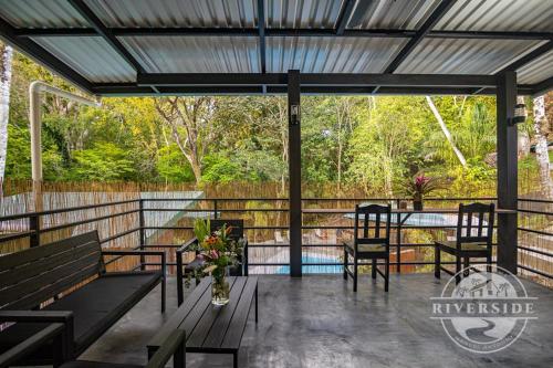 a patio with benches and a table and a pool at Riverside Villas in Manuel Antonio