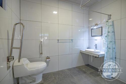 a white bathroom with a toilet and a sink at Riverside Villas in Manuel Antonio