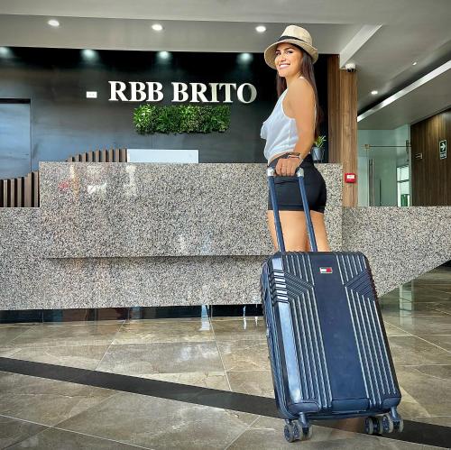 Una donna sta in piedi con i bagagli in un aeroporto di RBB BRITO HOTEL a Tarapoto