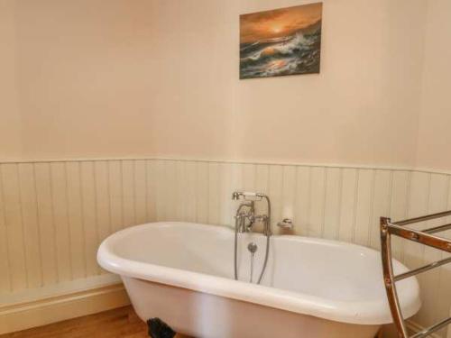 a white tub in a bathroom with a picture on the wall at Beautiful 3-Bed House in Longnor near Buxton in Longnor