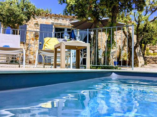 - une piscine avec une table et des chaises à côté d'une maison dans l'établissement Charmant Gîte Mazet Lo Garric, à Caux