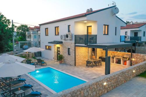 a villa with a swimming pool in front of a house at Villa Kaoru brand new Villa with a heated swimming pool in Malinska