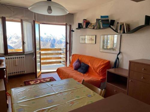 a living room with an orange couch and a table at Monolocale Bellavista in Prato Nevoso