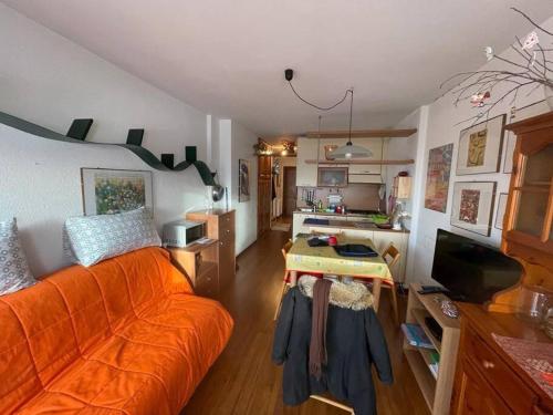sala de estar con sofá naranja y cocina en Monolocale Bellavista en Prato Nevoso