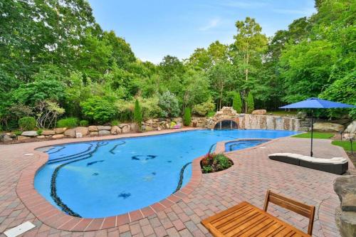 a large swimming pool with a brick patio and an umbrella at Amazing Pool Private Oasis! 25 Mins 2 Westhampton! in Wading River