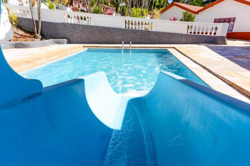 a blue swimming pool with a slide in a yard at Hotel Fazenda Aguas de Lindoia in Águas de Lindóia