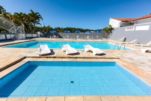 a swimming pool with two lounge chairs and a swimming pool at Hotel Fazenda Aguas de Lindoia in Águas de Lindóia