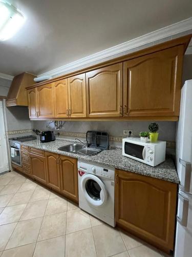 a kitchen with a washing machine and a microwave at Apartamento Xelb in Silves